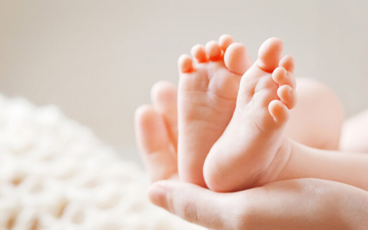 ママの手の上にのっている赤ちゃんの足の画像