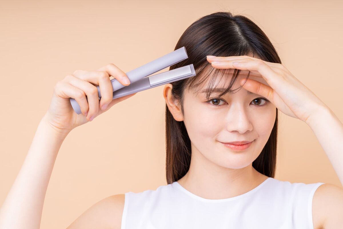 コードレスヘアアイロンで前髪をセットする女性