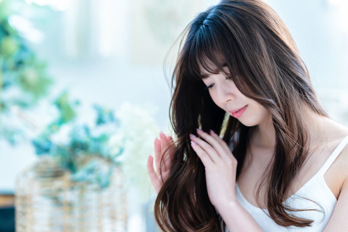 髪の毛を触る美髪女性の画像