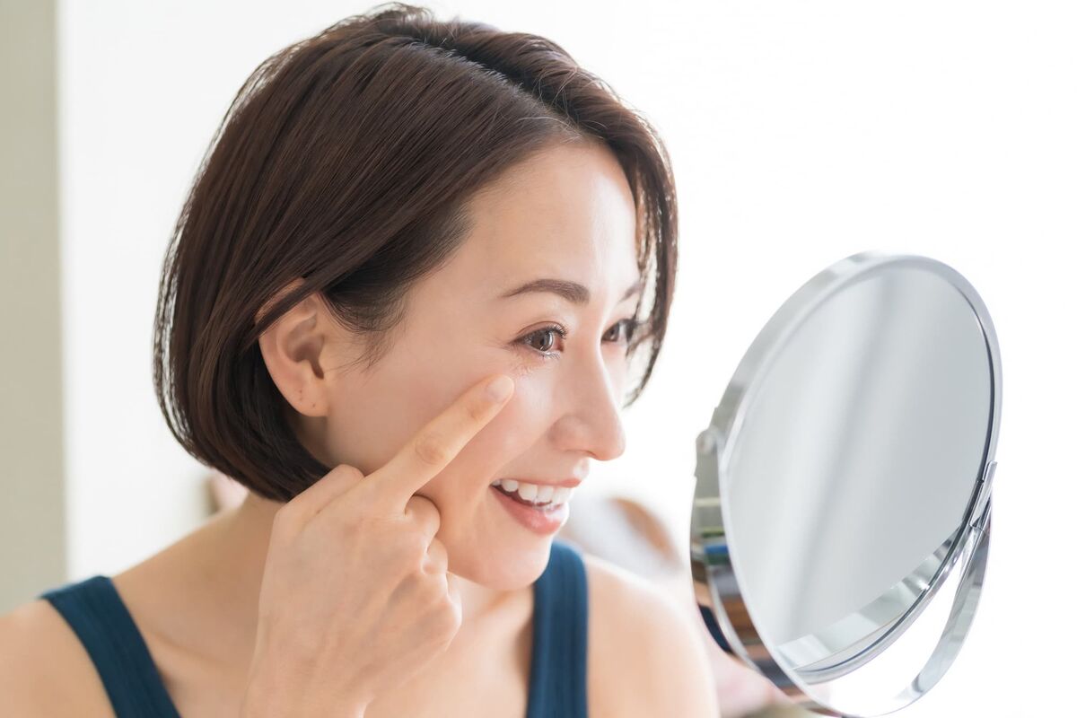 40代の女性が鏡で目元を見ている画像