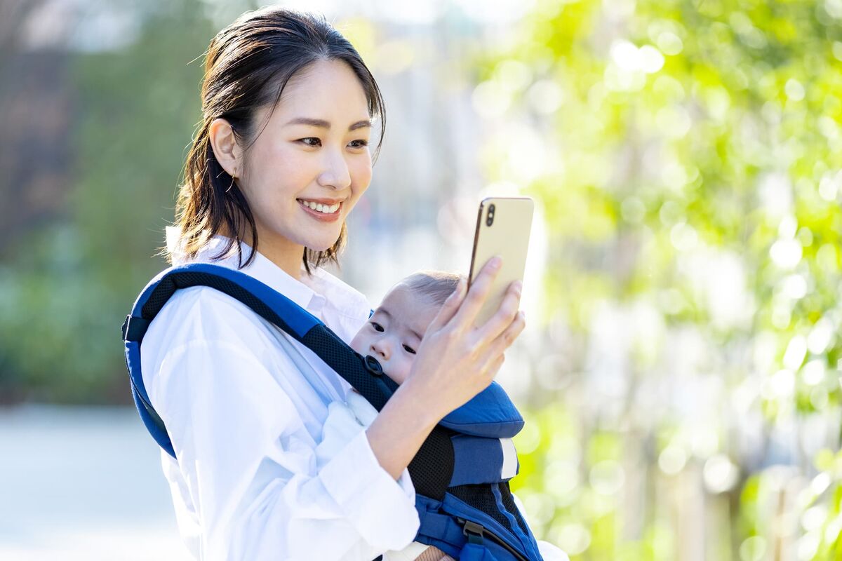 抱っこ紐で調べものをするママ
